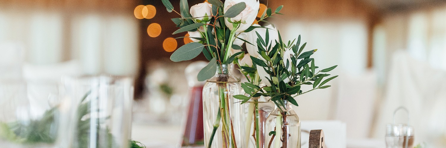 Glass bottles with white roses on table